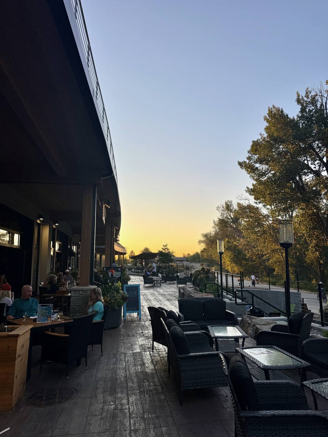 A restaurant terrace at The Boardwalk at dusk, tables out along the river walk