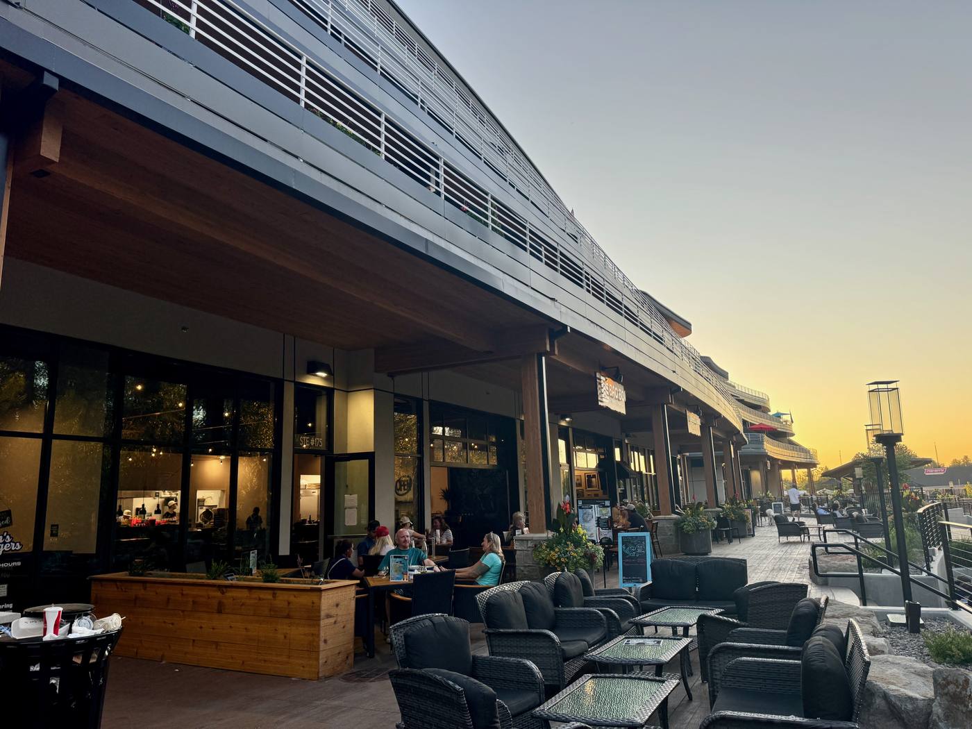 Storefronts and patios at The Boardwalk lit at sunset
