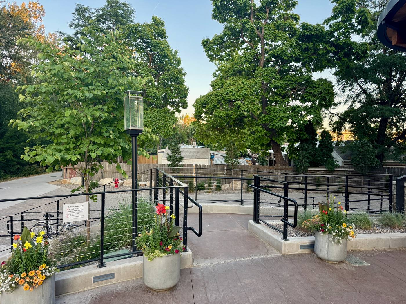 The Boardwalk's plaza with planters and cable railings, the Greenbelt running past